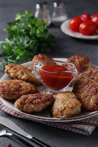 Cutlets of turkey fillet and oatmeal, fried in a pan, served with tomato sauce, Vertical image