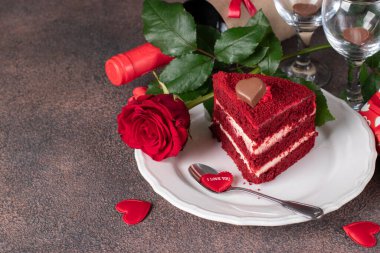 Piece of Red Velvet cake, bottle of wine, rose and gift for Valentines Day