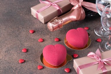 Homemade bright mousse cakes Hearts with pink velor coating, two glasses and champagne for Valentines Day, Copy space