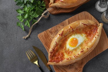Khachapuri in Adjarian, Open pie with suluguni cheese and egg yolk in the form of a boat on wooden board, Top view