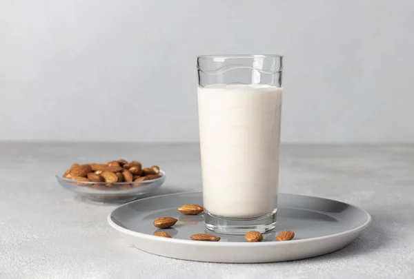 灰色の背景に背の高いガラスの新鮮なアーモンドミルク 健康的なビーガンミルク交換器 — ストック写真