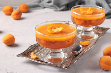 Açık gri arka planda iki şeffaf fincanda taze kayısı jölesi.