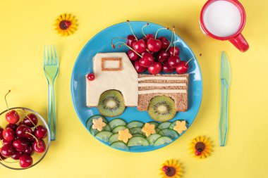 Sarı arka planda vişne, kivi, salatalık ve peynirli çocuklar için sağlıklı bir tost.