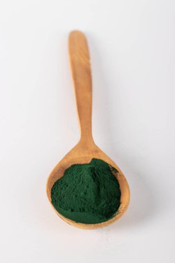 Beyaz arka planda tahta kaşıkta organik spirulina yosun tozu, dikey format