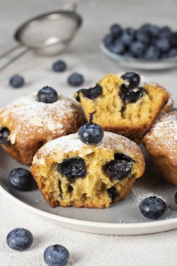 Yaban mersinli ev yapımı kekler ve gri tabakta pudra şekeri serpiştirilmiş bademler.