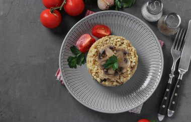 Bulgur garnitürü, gri tabakta domateslerle servis edilen şampiyonlarla süslenir.