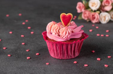 Kek. Kırmızı kadife. Gri arka planda pembe krema ve kurabiye kalbiyle süslenmiş.