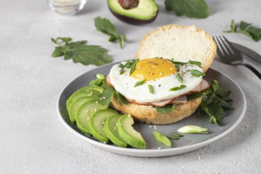 Kahvaltıda jambonlu ev yapımı sandviç, kızarmış yumurta ve avokado.