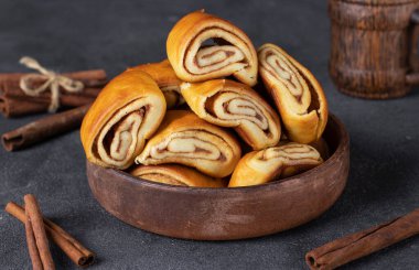 Tarçınlı rulo ve gri arka planda bir fincan kahve, yakın plan.