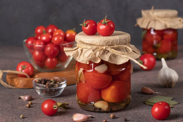 褐色桌子上的两个玻璃瓶里夹着大蒜的酸樱桃西红柿 — 图库照片