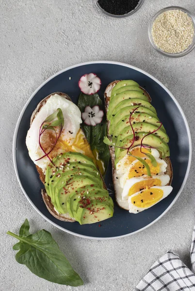 stock image Healthy breakfast - sandwiches with avocado, egg and sesame on round plate, Top view