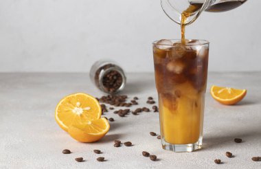 Açık gri arka planda buzlu karışık kahve. Soğuk kahve, portakal suyu ve şurupla bir bardağa doldurulur.