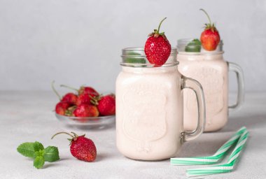 Mason kavanozlarında açık gri arka planda çilekli ev yapımı smoothie.
