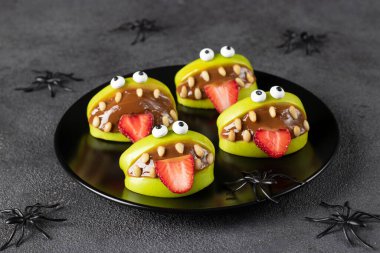 Cadılar Bayramı partisi için örümceklerle süslenmiş gri arka planda ürkütücü yeşil elma canavarları.