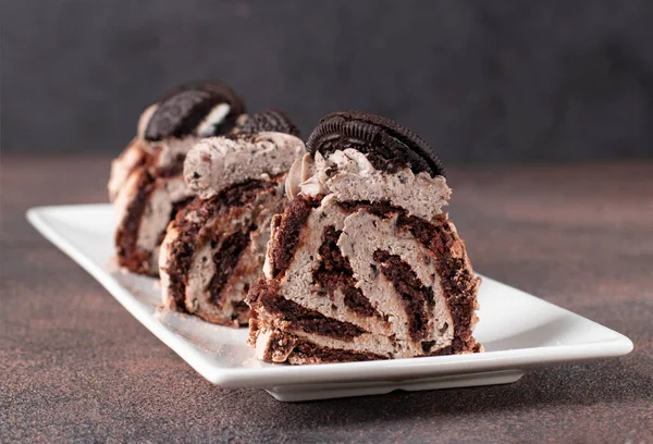Нарезанный Шоколадный Безе Рулон Печеньем Белой Тарелке Коричневом Фоне — стоковое фото