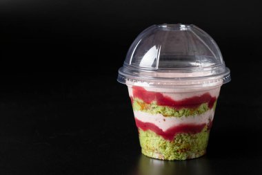 İçinde şam fıstığı, çilekli krema ve siyah arka planda çilekli pasta, mesaj için yer var.