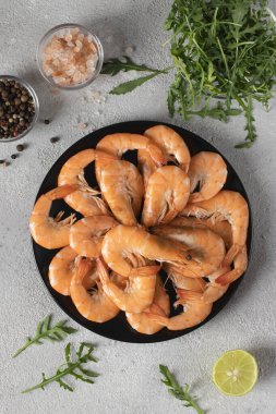 Yuvarlak tabakta kaynamış karides ve gri arka planda baharatlar, Üst Manzara