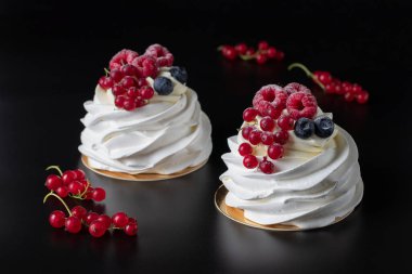 Mini Pavlova pastası, ahududu, yaban mersini ve kırmızı fonda kuşüzümü, yakın plan.