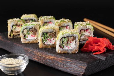 Siyah arka planda tahta üzerinde yılan balığı ve Philadelphia peynirli Rolls Green Dragon.