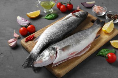 Çiğ deniz kabuğu ve fesleğen, limon, tuz, biber, kiraz domatesleri ve ahşap ahşap zemin üzerinde sarımsak gibi baharatlar.