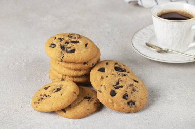 Gri arka planda çikolatalı kurabiye ve bir fincan kahve, yakın plan.