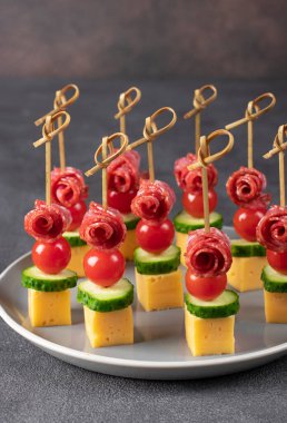 Kiraz domatesli kanepe, sosis, peynir ve salatalık gri tabakta, dikey görüntü