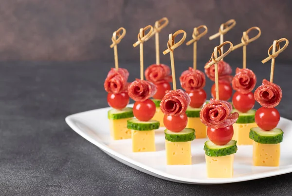 Vişneli domates, sosis, peynir ve salatalıkla beyaz tabakta kaplan.