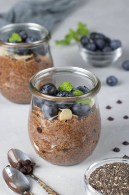 Chocolate chia pudding with blueberry and almonds in glass jars on gray background. Healthy food