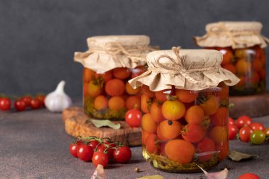 Kahverengi masadaki cam kavanozlarda salamura domates.