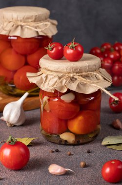 Kahverengi masada iki cam kavanozda sarımsaklı vişneli domates turşusu.