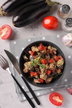 Meat stew with eggplant and tomatoes served in dark bowl on gray background