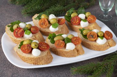 Ton balıklı pate, mozzarella, zeytin ve beyaz tabakta vişneli domates.