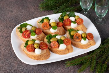 Ton balıklı pate, mozzarella, zeytin ve beyaz tabakta vişneli domates.