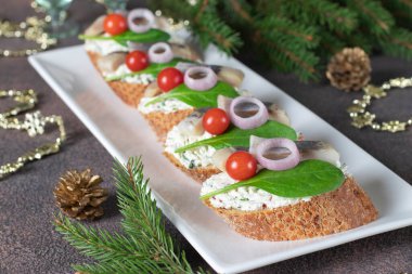 Beyaz tabakta ringa balığı, krem peynir, ıspanak ve vişneli domates.