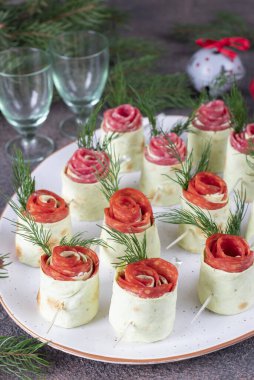 Krem peynirli lahanalı güller, sosisli sucuk ve beyaz tabakta salam.