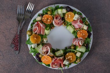 Jambon, mandalina, roka, dor bleu peyniri, salatalık ve çam fıstıklı çelenk şeklinde salata.