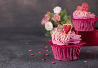 Kekler koyu arkaplanda pembe krema ve kurabiye kalpleriyle süslenmiş kırmızı kadife.