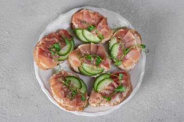 Yumuşak peynirli sandviçler, jambon ve salatalıklı gri arka plan, Üst Manzara