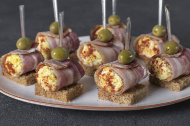 Pancetta yumurtalı ve işlenmiş peynirli rulo ekmekli tost ve beyaz tabakta.