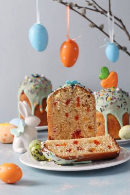 Pastel mavi arka planda turuncu ve mavi renkli yumurtalarla kesilmiş Paskalya pastası.