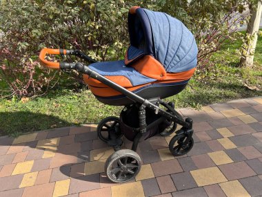 Denizci mavisi bebek arabası ve yeni doğmuş bebek şehir parkında yürüyor.