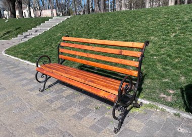 Şehir parkındaki bir ara sokakta bulunan ahşap bank.