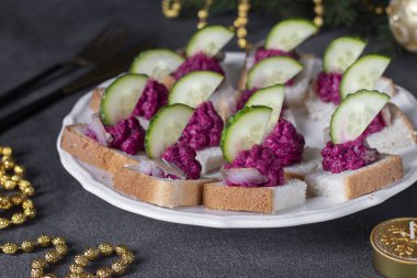 Tuzlu ringa balığı, pancar kreması ve gri arka planda beyaz tabakta salatalık.