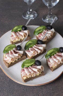 Pastırmalı sandviç, salatalık ve çavdar ekmeğinden siyah zeytin.