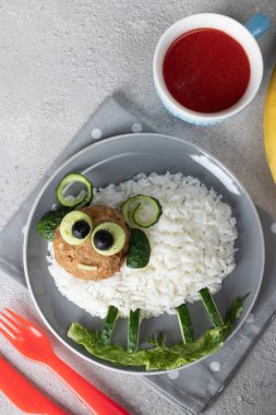 Çocuklar için yaratıcı bir kahvaltı. Pirinç, pirzola, salatalık ve koyun şeklinde zeytin.