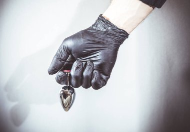 Seksi adam elinde bir BDSM anal tıkacı tutuyor. Bu ürün sadece yetişkinler için.