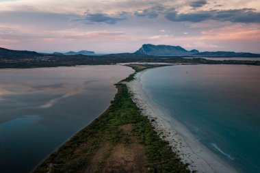 San Teodoro sand beach with lagoon, mountain of island Tavolara and coastline in Sadinia Italy from above during sunset, clouds in sky