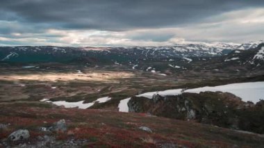 Timelapse video of mountain landscape of Jotunheimen National Park with red moss and dark sky with moving clouds during sunset in Norway