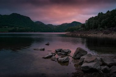 Cloudy purple sunset on calm lake with mountains in Norway near Stavanger