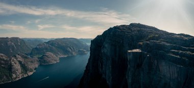 Panorama landscape of Preikestolen rock with view into Lysefjord in Norway, steep cliff in the mountains with a platform, sunny day with blue water in the fjord